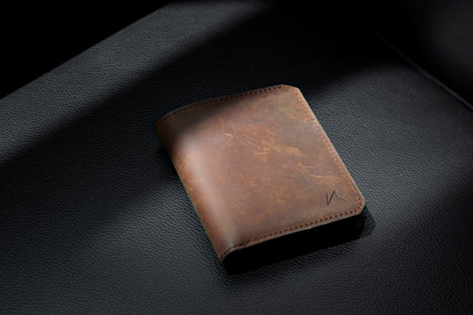 Brown leather bifold wallet on black leather surface